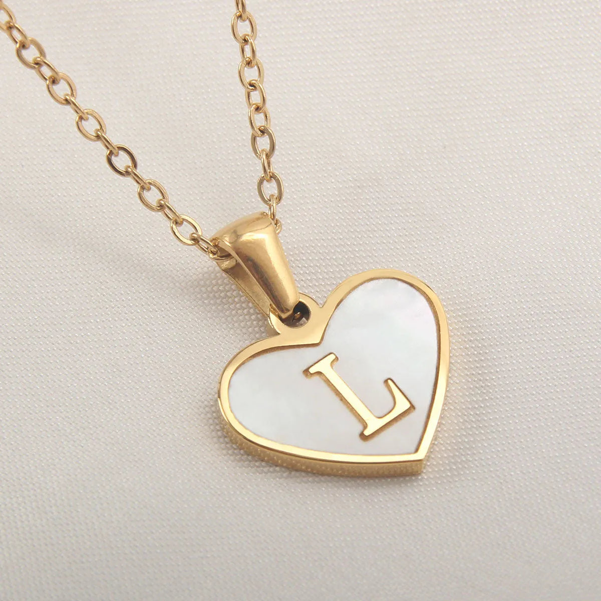 Gold-plated heart necklace with white shell pendant personalised with a letter, on an adjustable chain.