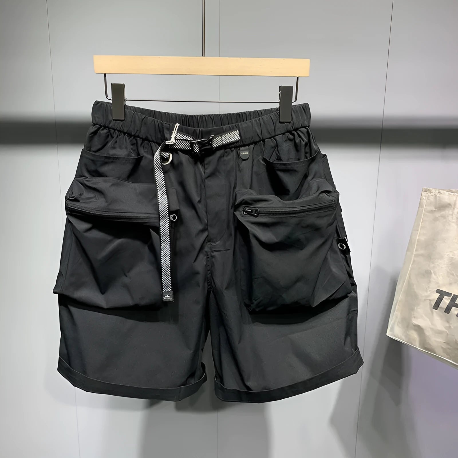 Man wearing loose fit black workwear shorts with pockets, showing above-the-knee length and straight leg style.