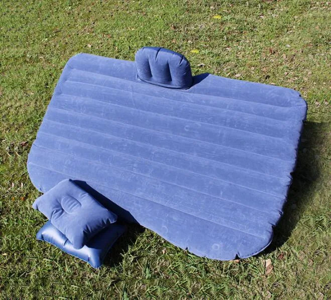 Inflatable car bed with flocked surface and two pillows, shown folded next to its storage bag.