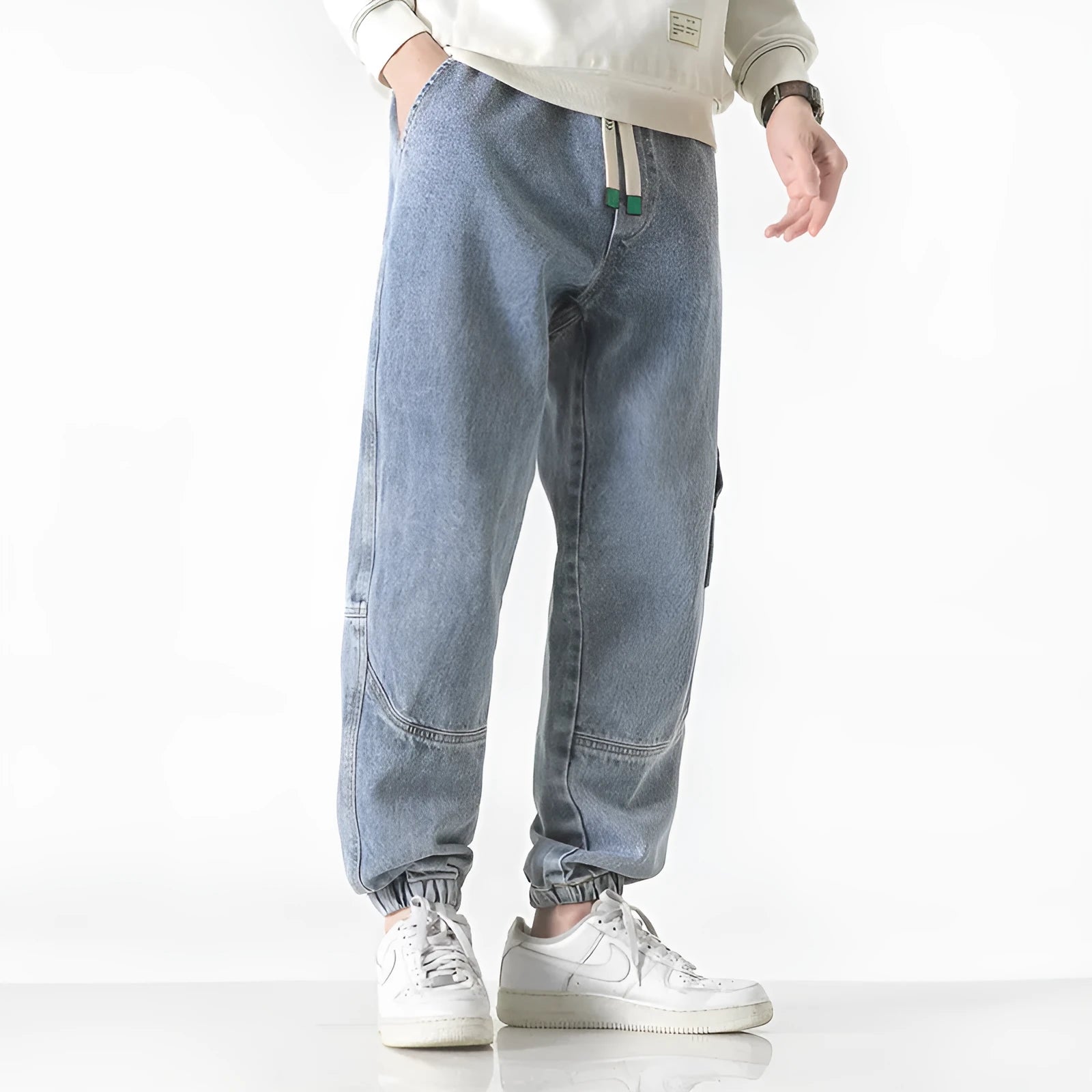 Men's loose fit tapered cotton trousers in black, shown on a model, featuring a mid-waist and tapered leg design.