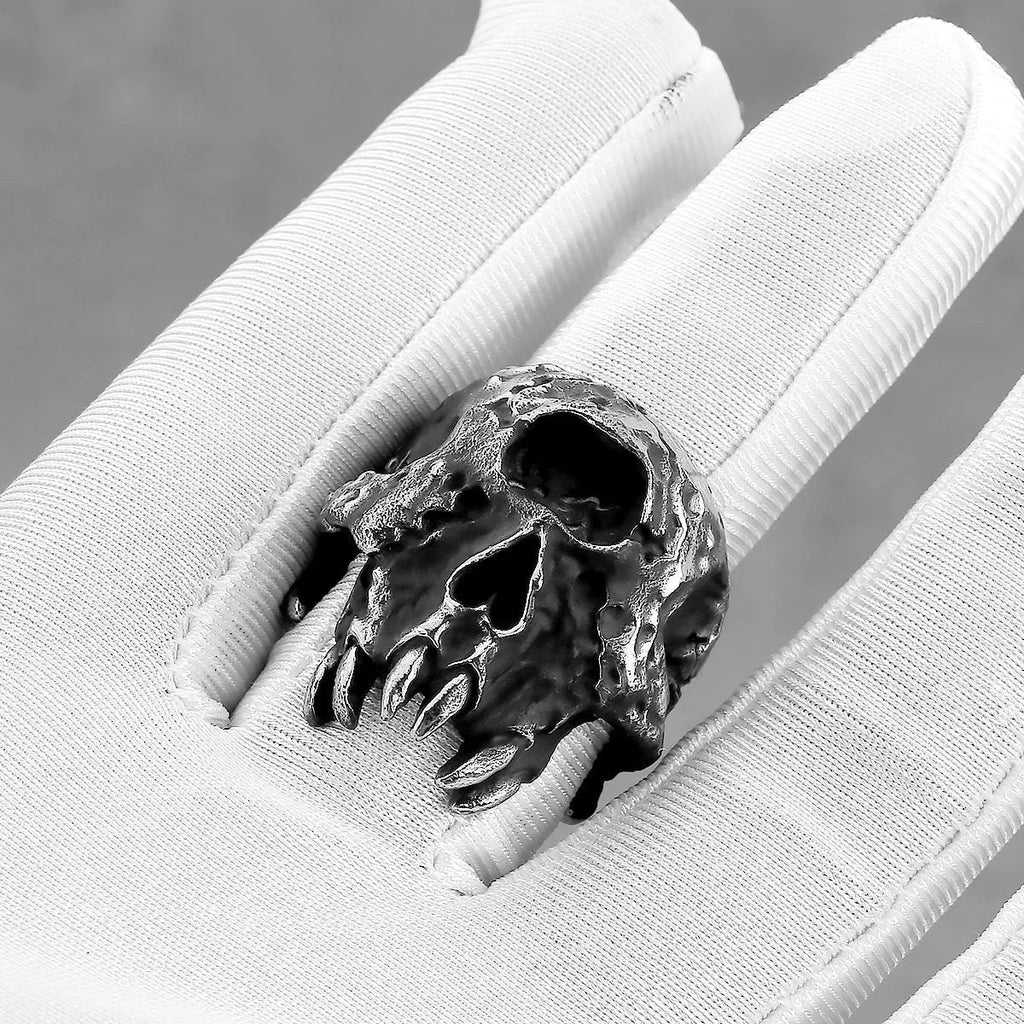 Close-up of a silver-toned alloy ring with a detailed one-eyed skull design on the finger.
