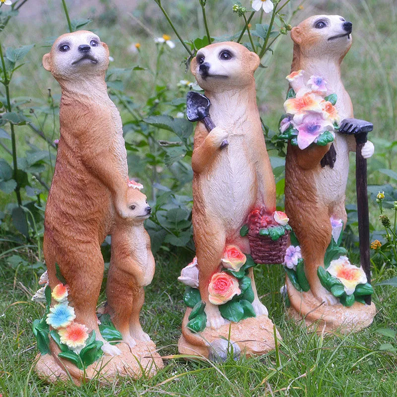 Three small straw hat mongoose garden ornaments: one with a baby, one holding a rake, one holding a shovel.