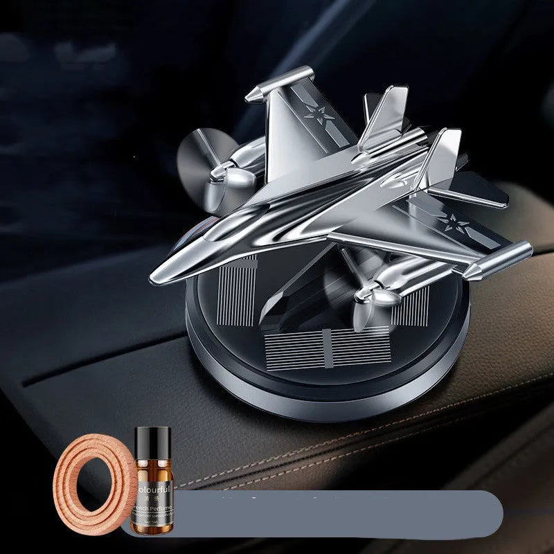 Silver solar powered rotating fighter aircraft perfume ornament on a table.