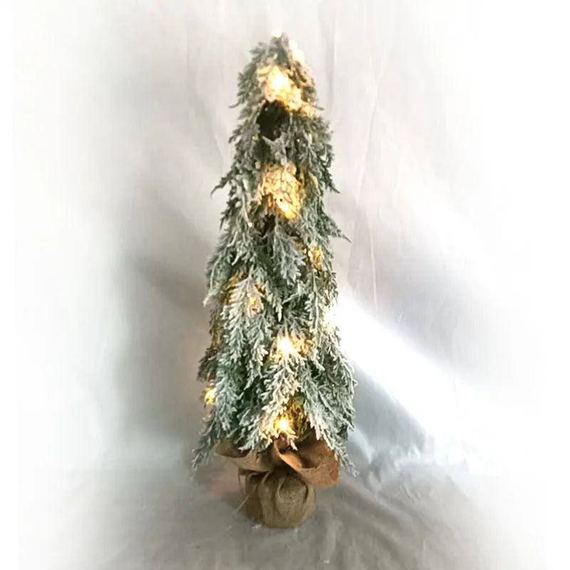 Small white artificial Christmas tree with snowy textured branches and built-in lights on a desktop