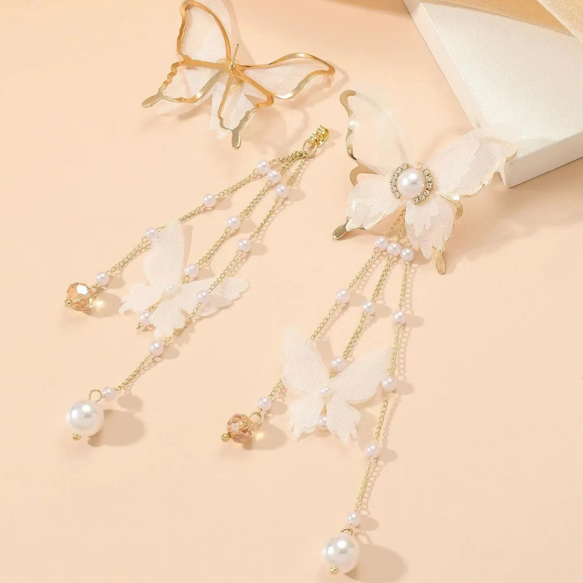 White butterfly-shaped earrings with tassels, pearls, rhinestones, and lace details on electroplated copper alloy