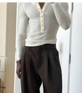 Man wearing a cream-coloured ribbed long-sleeve henley top with a three-button placket.