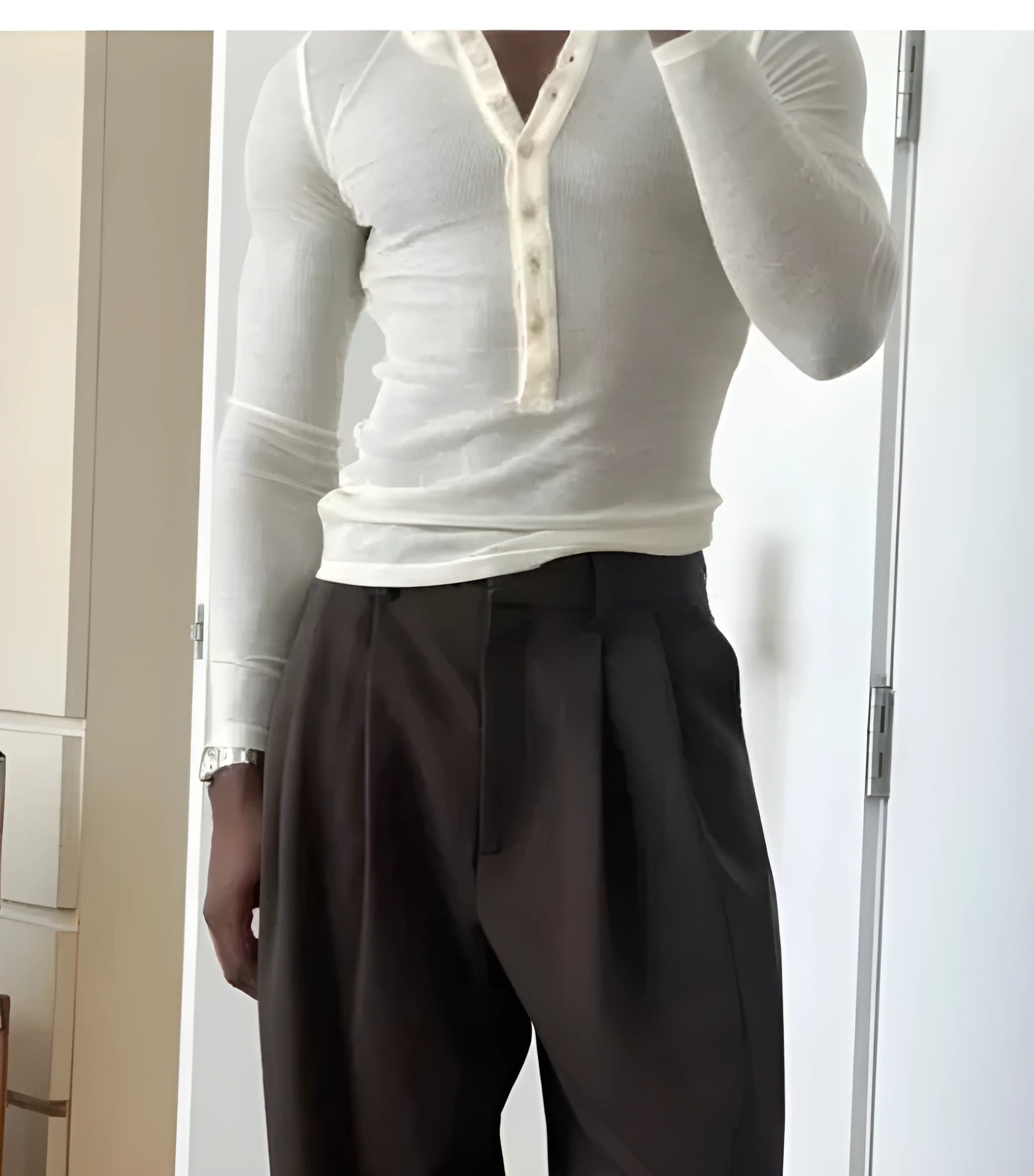 Man wearing a cream-coloured ribbed long-sleeve henley top with a three-button placket.