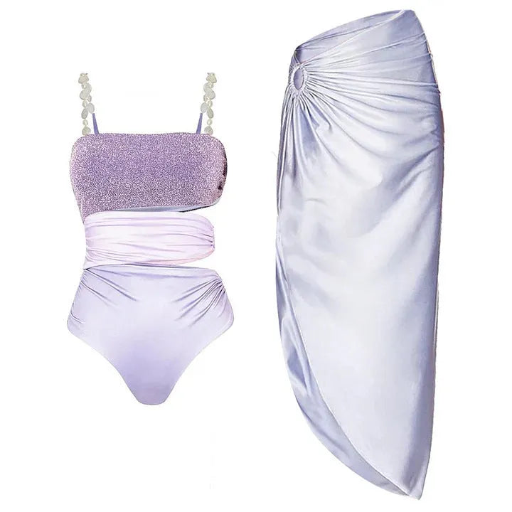 Purple one-piece swimsuit with coordinating wrap skirt set on beach background