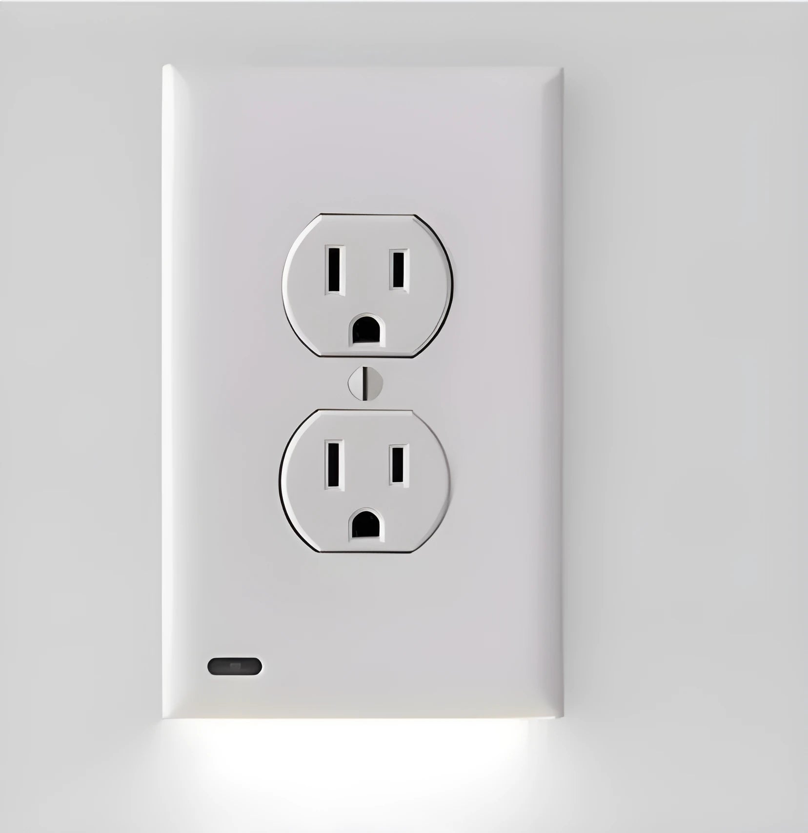 White plug-in socket induction night light with automatic sensor installed in a wall outlet.