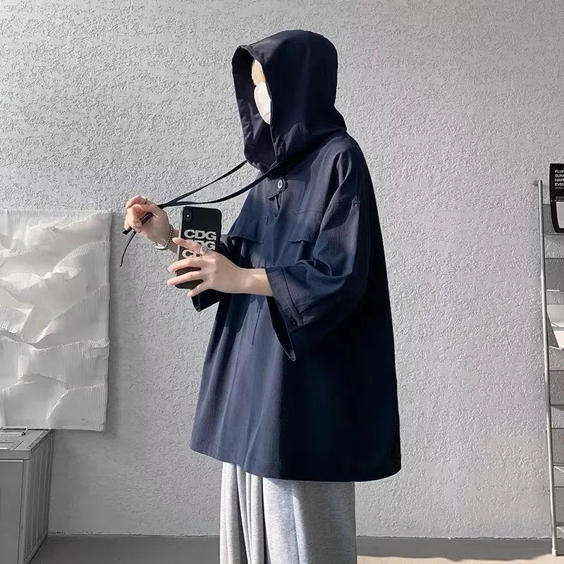 Man modelling a loose grey hooded short sleeve t-shirt, showing the pullover style and front design.