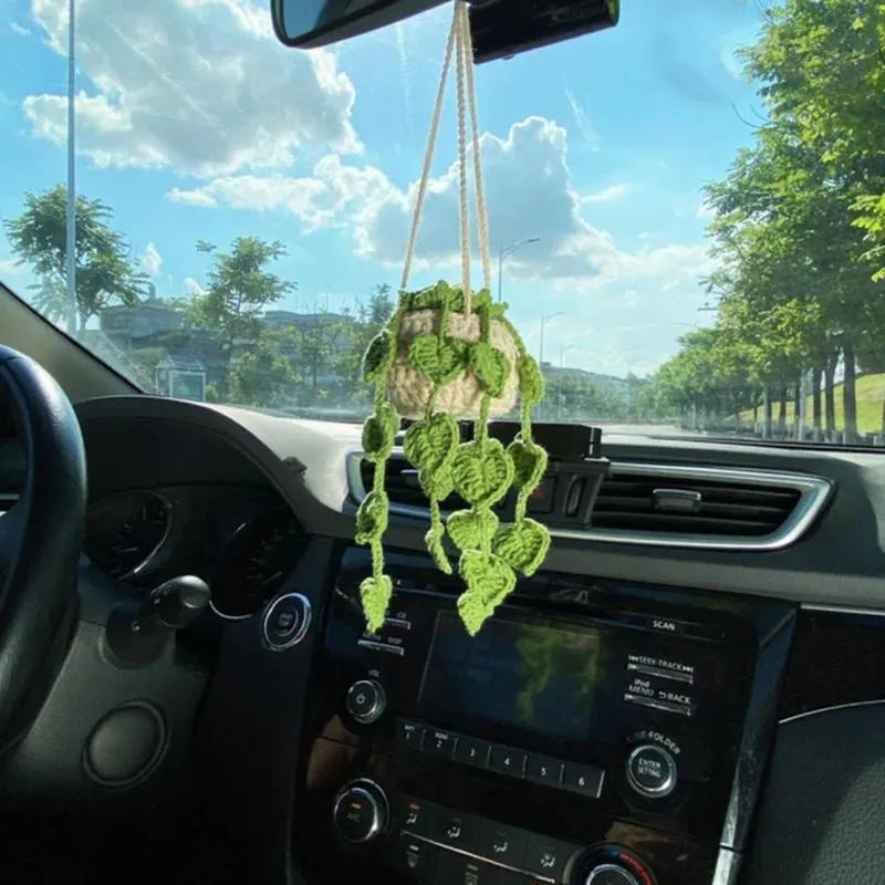 Green and white knitted wool car plant decoration with hanging rope on car dashboard