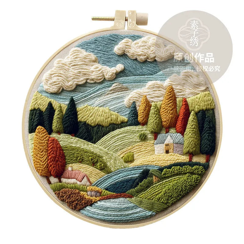 DIY landscape embroidery kit with cotton fabric, bamboo frame, threads and needles arranged for crafting
