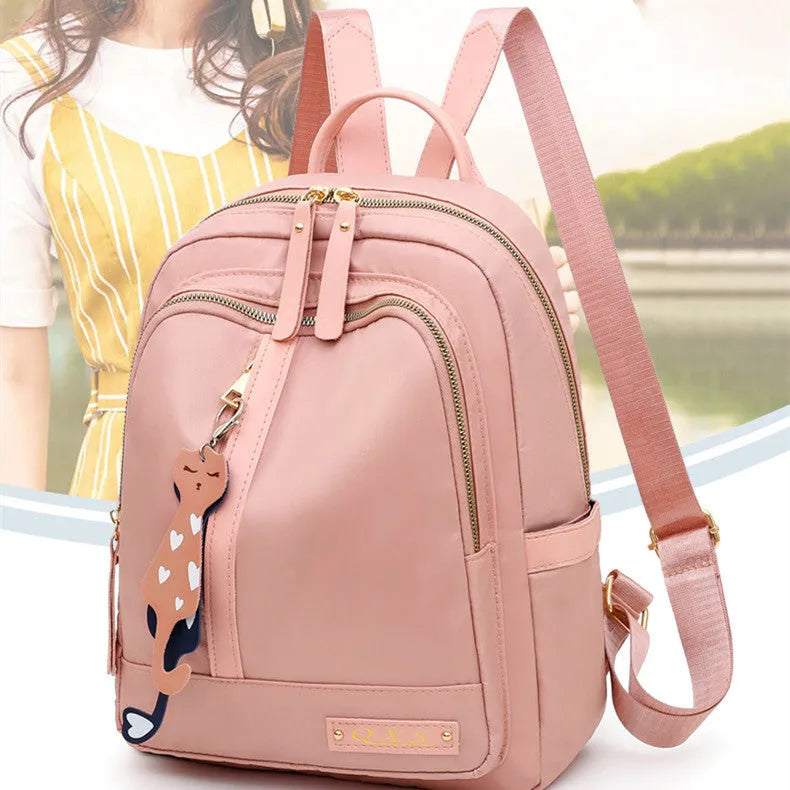 Black nylon casual travel backpack with double shoulder straps, external pockets, and a soft handle on a solid background.