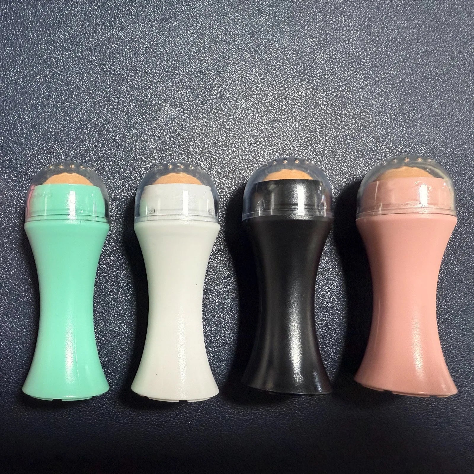 Volcanic stone facial roller for oil control in black, green, pink and white colour options.