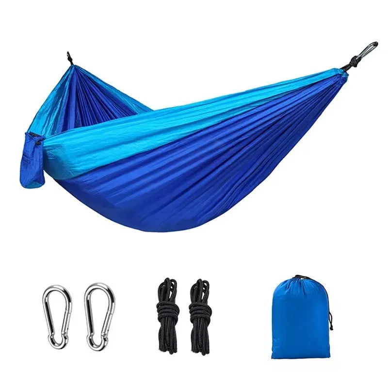 Blue parachute nylon camping hammock hanging between trees with 300kg capacity
