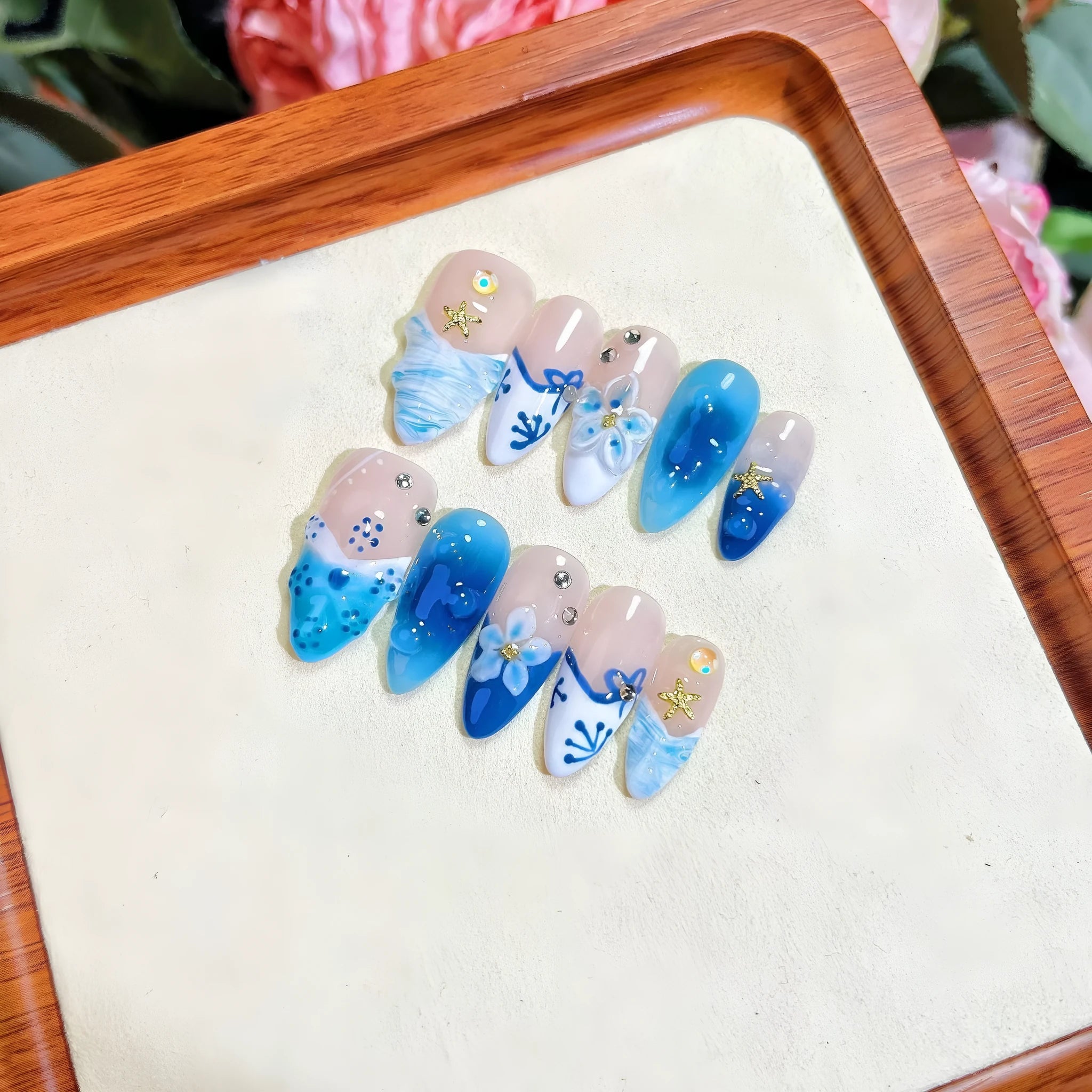 Set of blue carved plastic wearable artificial nails showing hand-painted summer ice design, laid out in sizes XS, S, M, L
