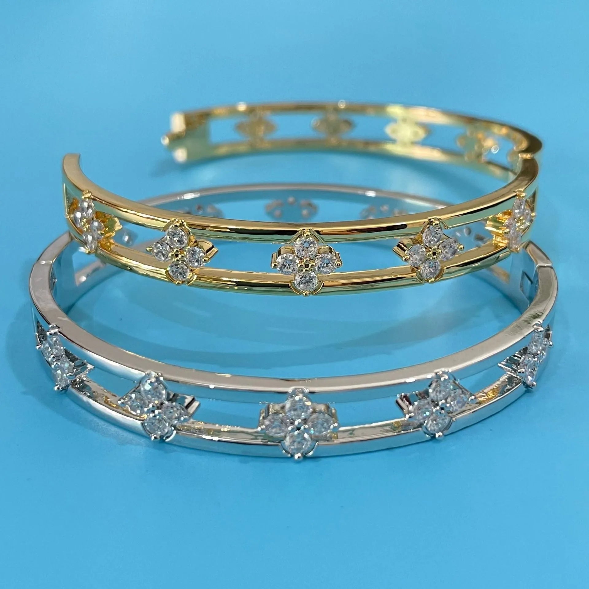 Gold or silver adjustable hollow bracelet with a four-leaf clover charm inlaid with a zircon stone.
