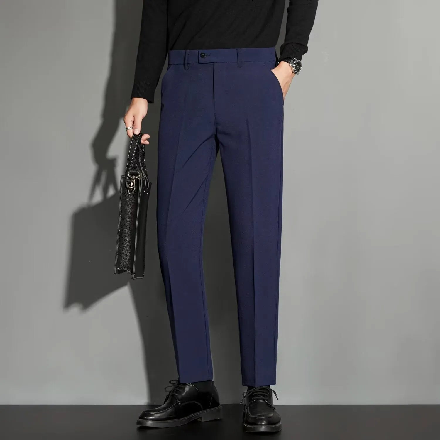 Man wearing straight leg ankle-length suit trousers in a light colour, showing the drape of the fabric.