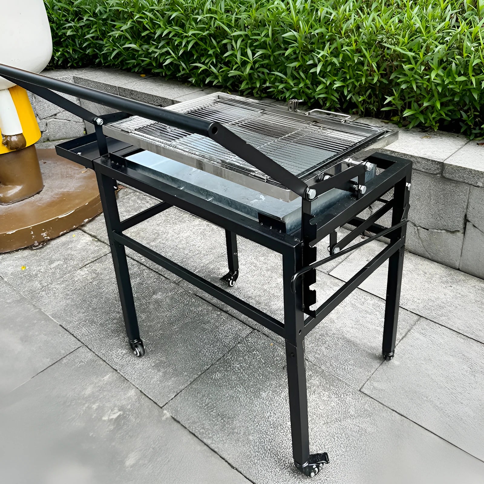Large foldable charcoal barbecue grill stove shown in outdoor courtyard setting
