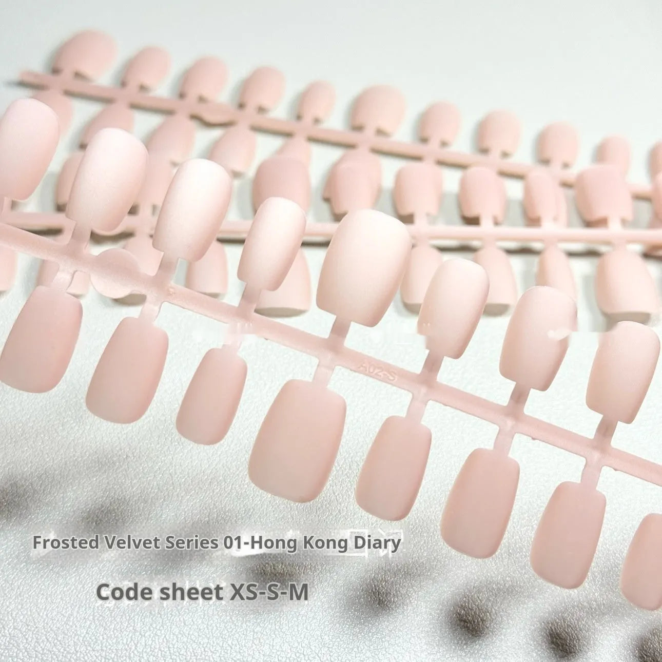 Set of frosted velvet Cat's Eye false nail wraps in short ladder sizes XS, S, and M on a display stand.