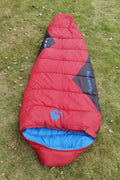 Outdoor cotton sleeping bag in Army Green with its compression storage sack laid beside it.