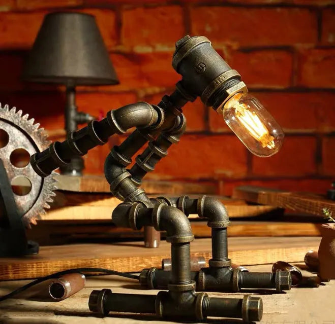 Green bronze vintage robot table lamp with industrial iron pipe design on wooden desk