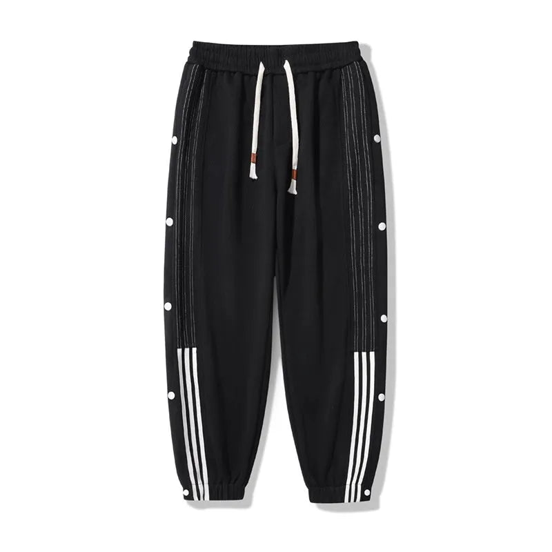 Man wearing loose grey cotton blend sweatpants with ankle ties and a drawstring waist.