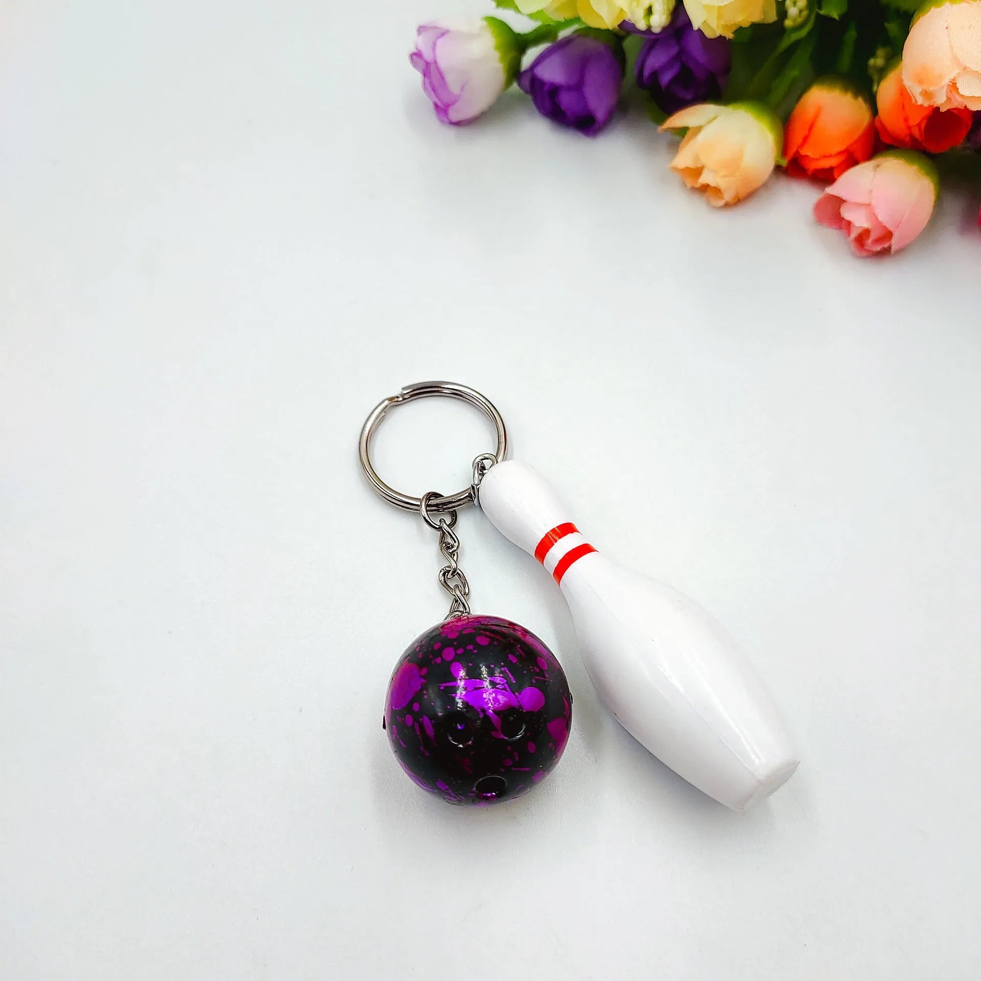 Mini sports bowling keychain pendant in PVC metal, shown in dark red, blue, purple, and green colour options.