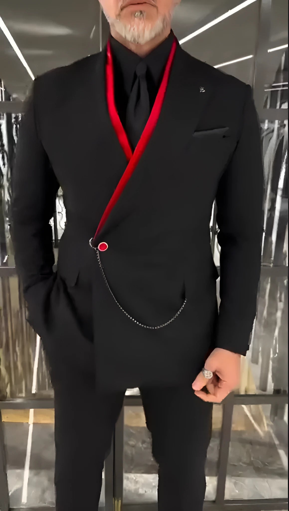 Black double-layered jacket with red inner lining and front chain detail on flat background