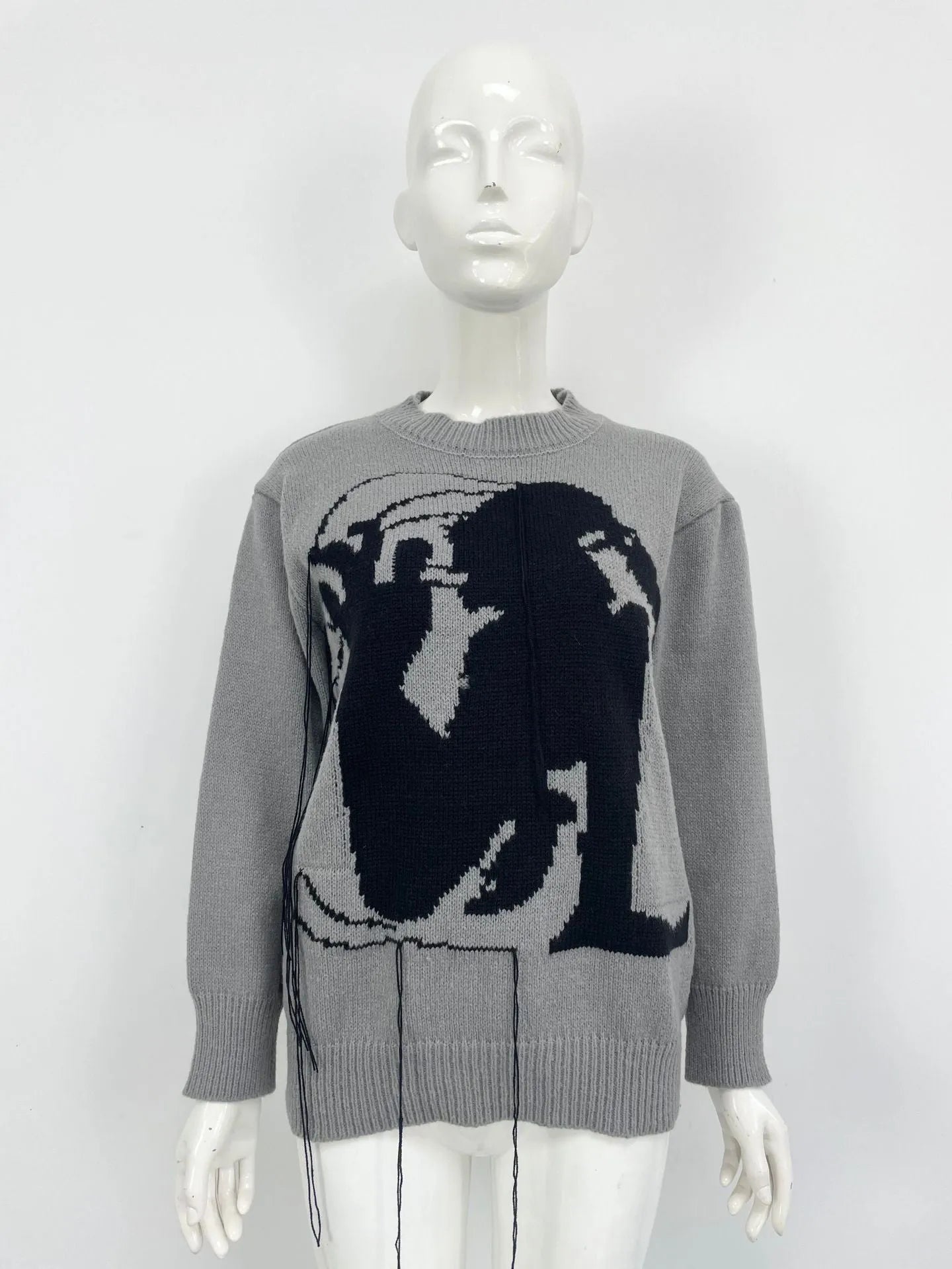 Grey women's alpaca wool pullover sweater with abstract pattern and tassel detailing on a hanger.