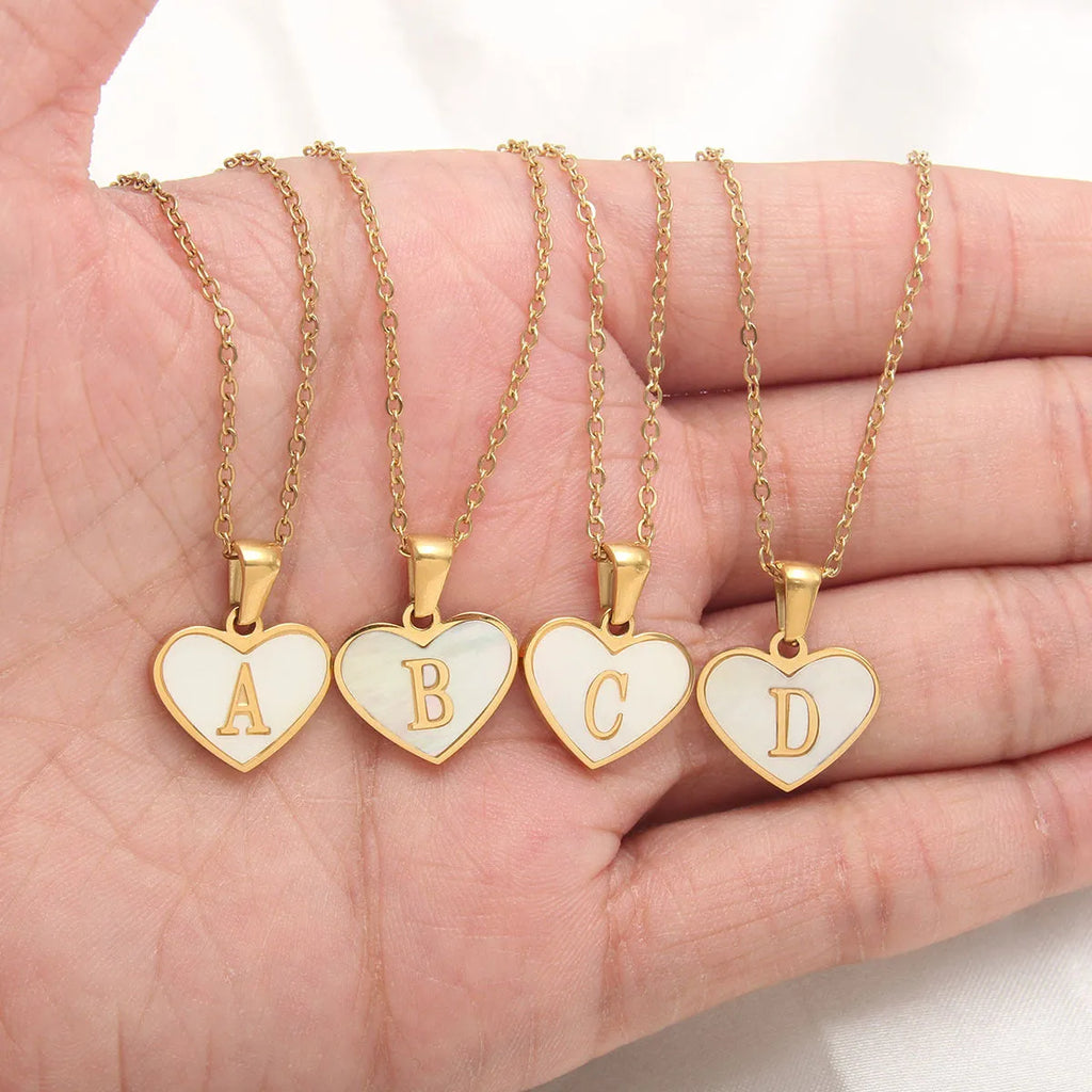 Gold-plated heart necklace with white shell pendant personalised with a letter, on an adjustable chain.