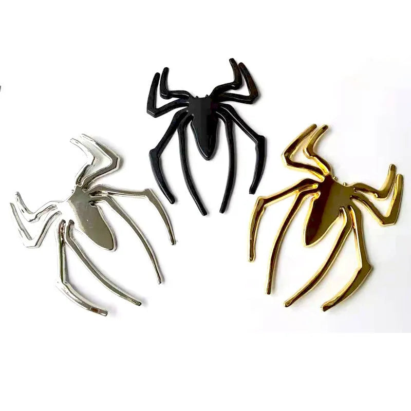 Three-dimensional metal spider-shaped bumper sticker in silver finish on a white background.