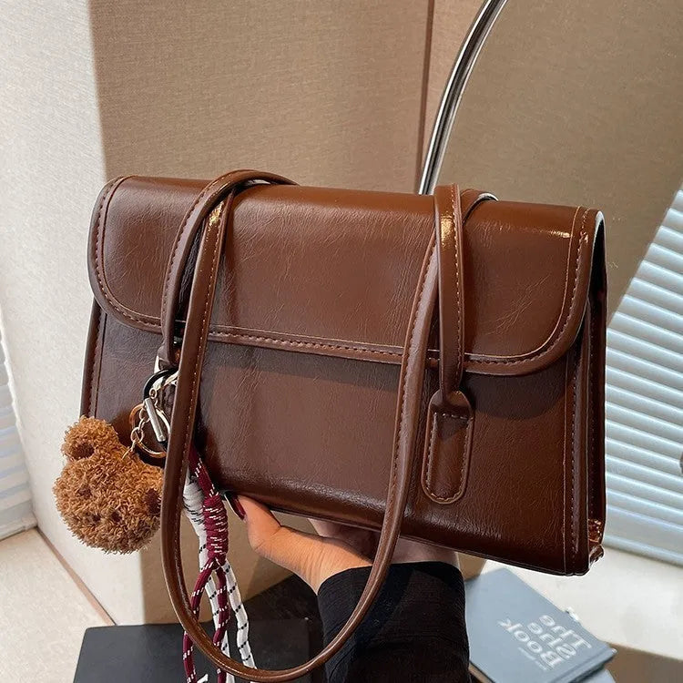 Brown women's structured square PU leather shoulder bag with a detachable tassel pendant and double straps.