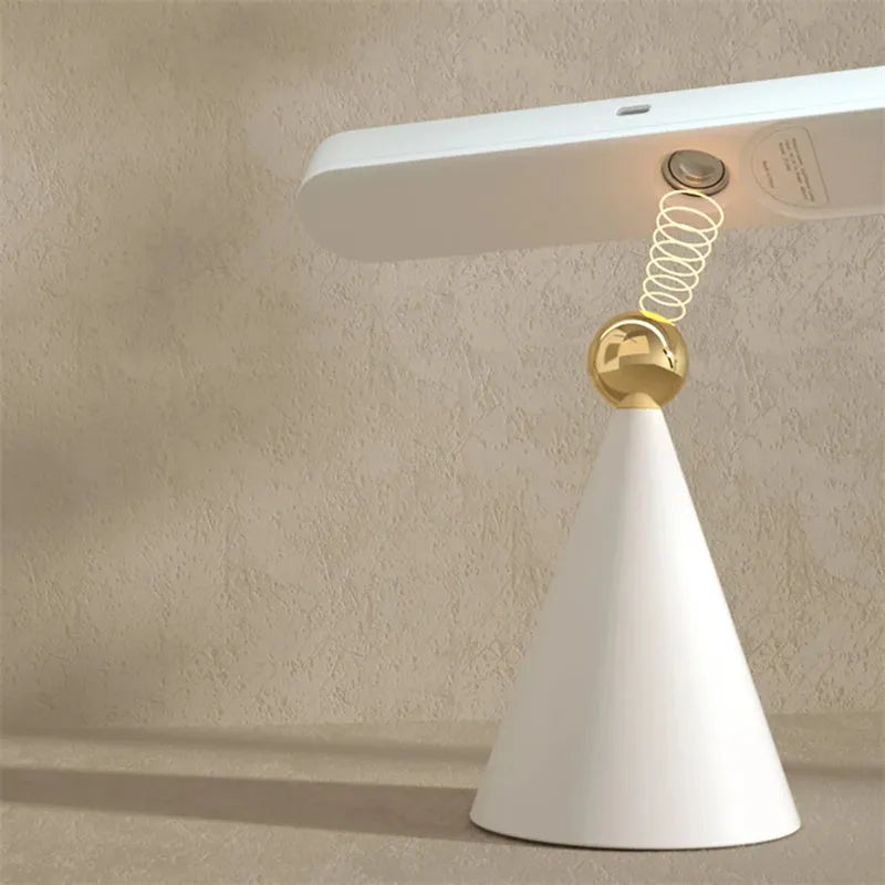 White geometric USB desk lamp with magnetic base shown on a wooden desk.