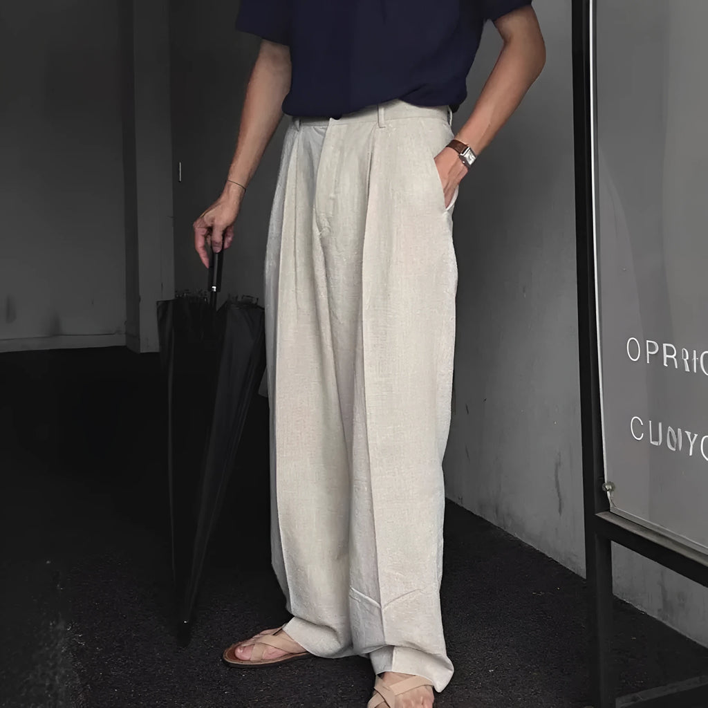 Men's lightweight apricot coloured wide-leg cotton linen trousers with a pencil leg opening on a hanger