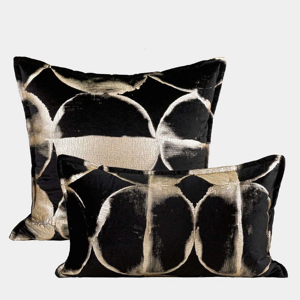 Black and gold abstract patterned flannel cushion in square and bolster sizes on a grey sofa.