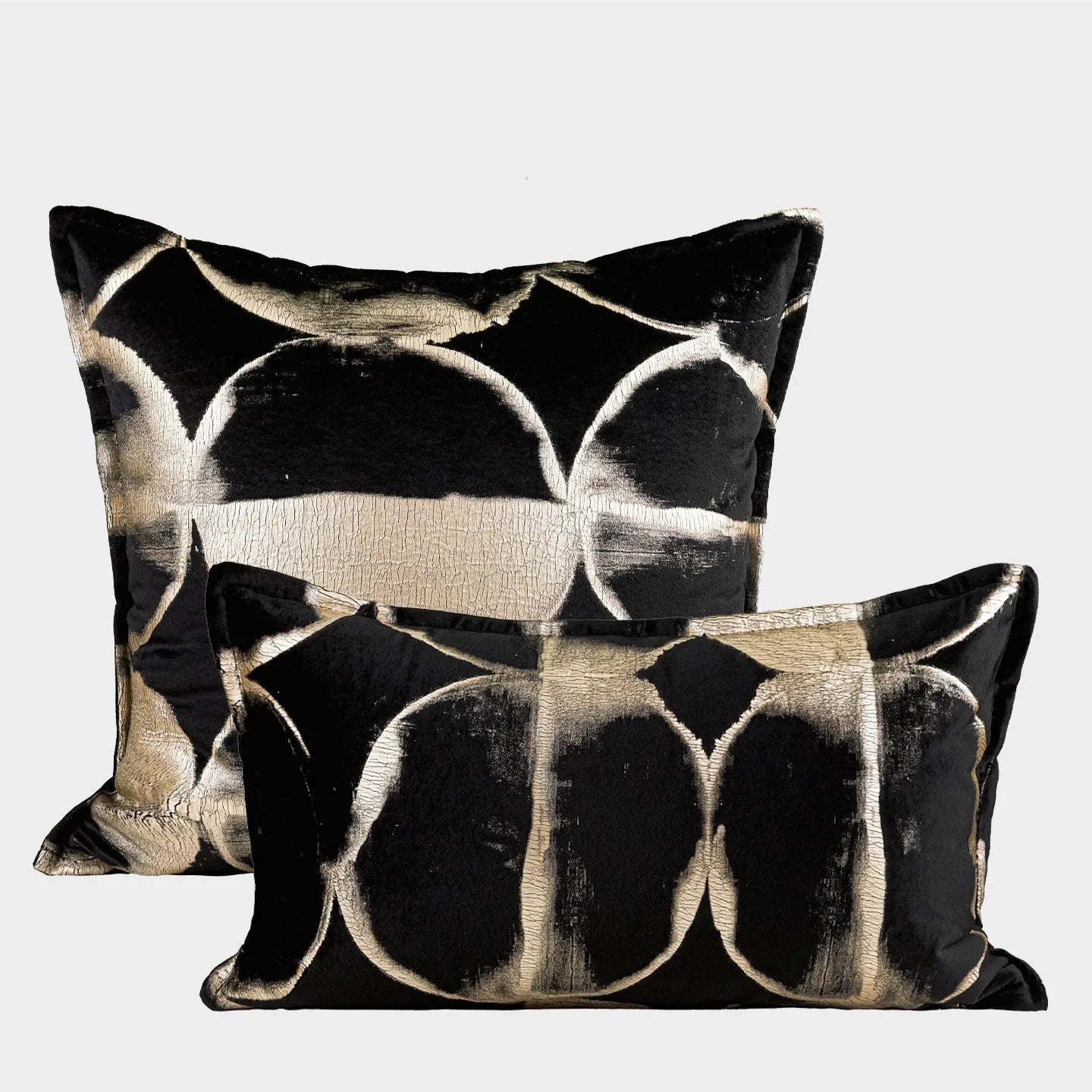 Black and gold abstract patterned flannel cushion in square and bolster sizes on a grey sofa.