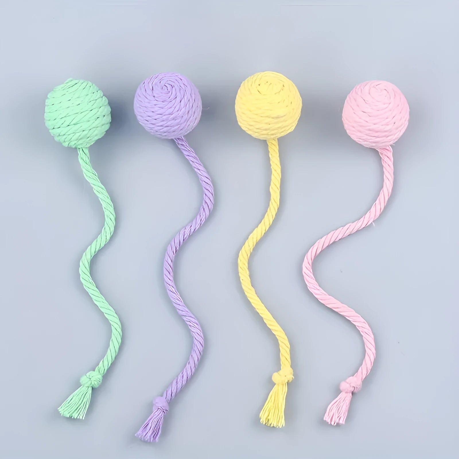 Coloured cat toy ball with rope attached and built-in bell inside, shown in green, pink, purple, and yellow options