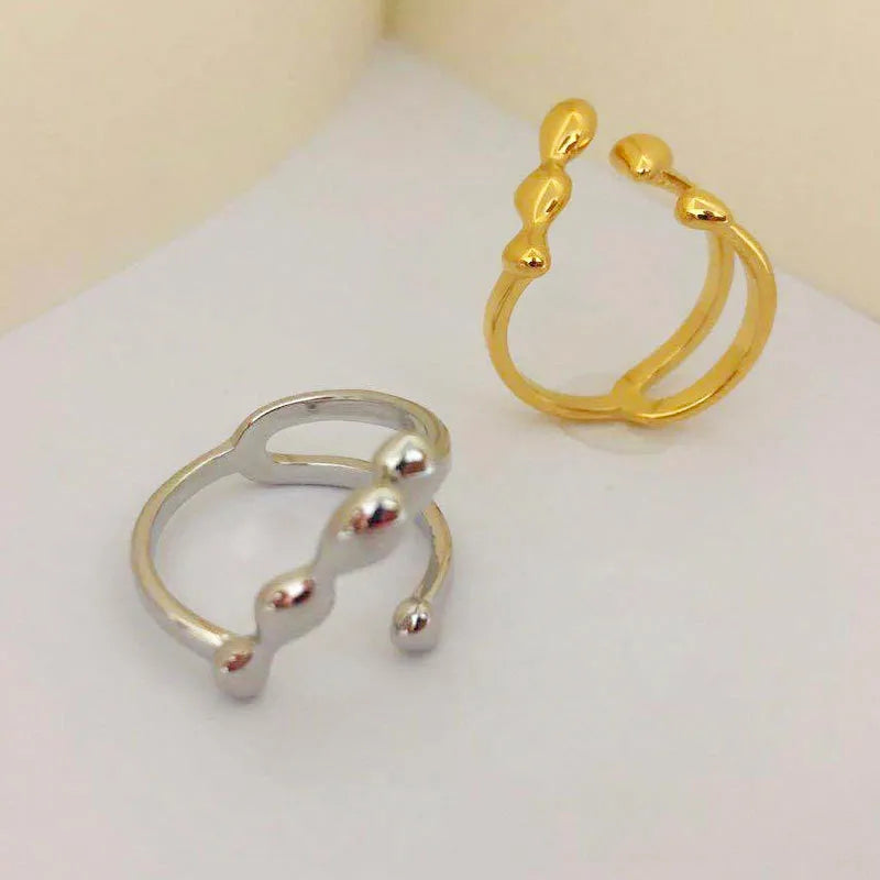 Gold or silver brass opening ring with spherical design elements on a model's finger.