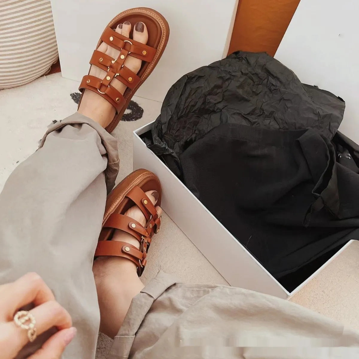 Women's brown patent leather Roman sandal slippers with sheepskin upper on a white background.