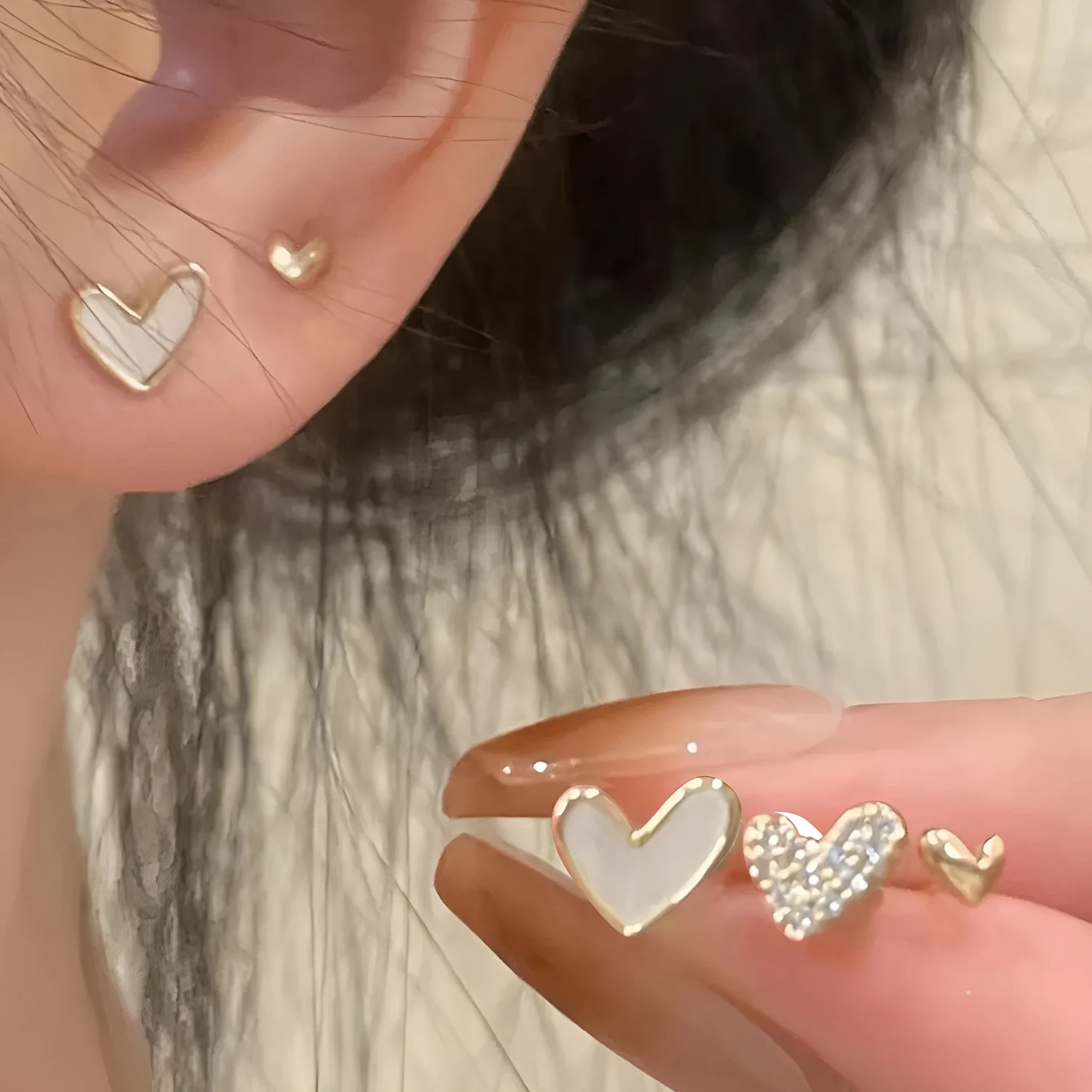 Set of three pairs of women's heart-shaped stud earrings in gold, black, white, and pink.
