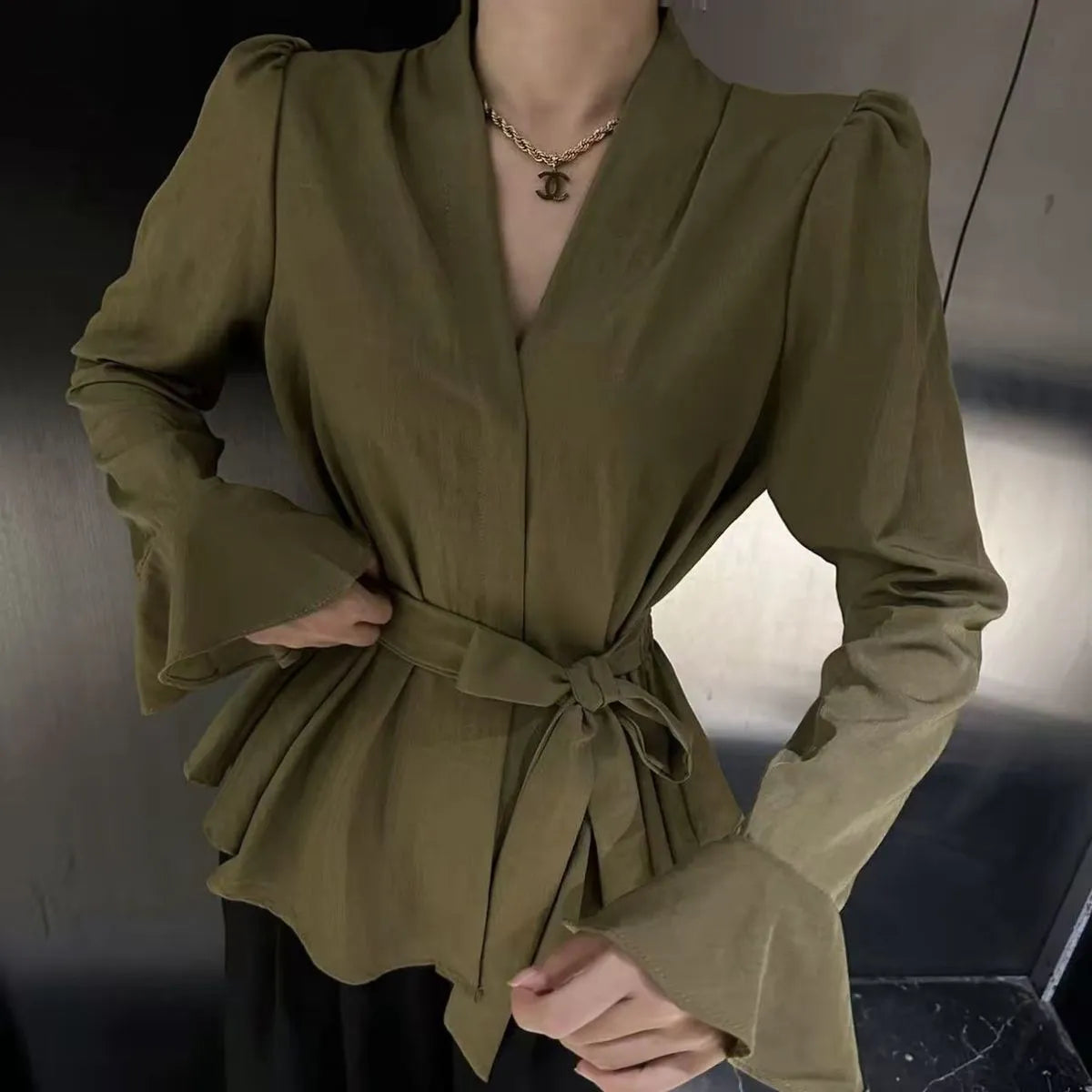 Woman wearing a wine red long sleeve shirt with an irregular French collar, bell sleeves, and a tie front.