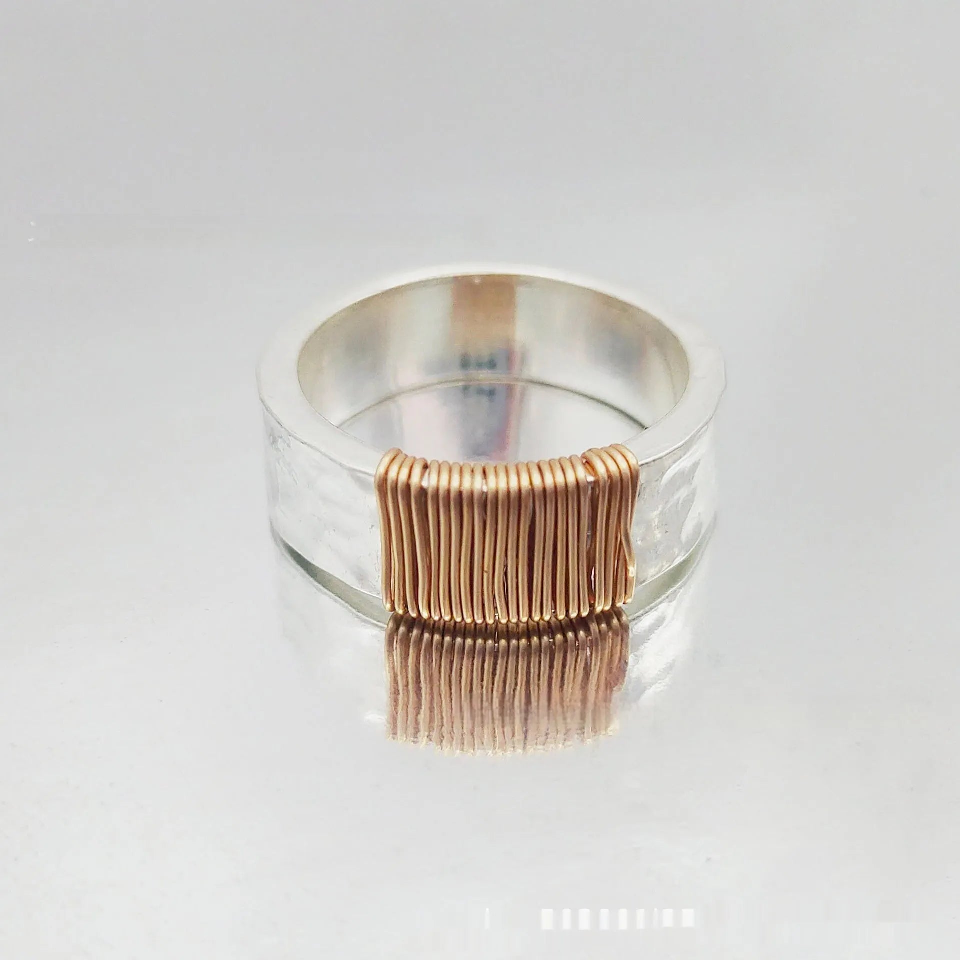 Copper wide face ring with irregular coil design in silver-gold colour.