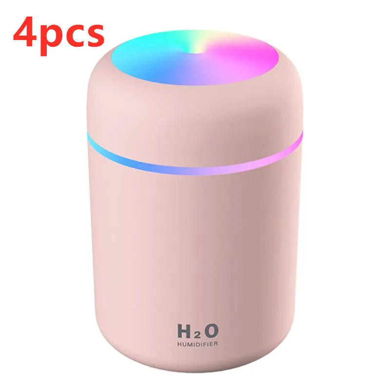 Pink USB mini humidifier with LED lights and water tank on desk