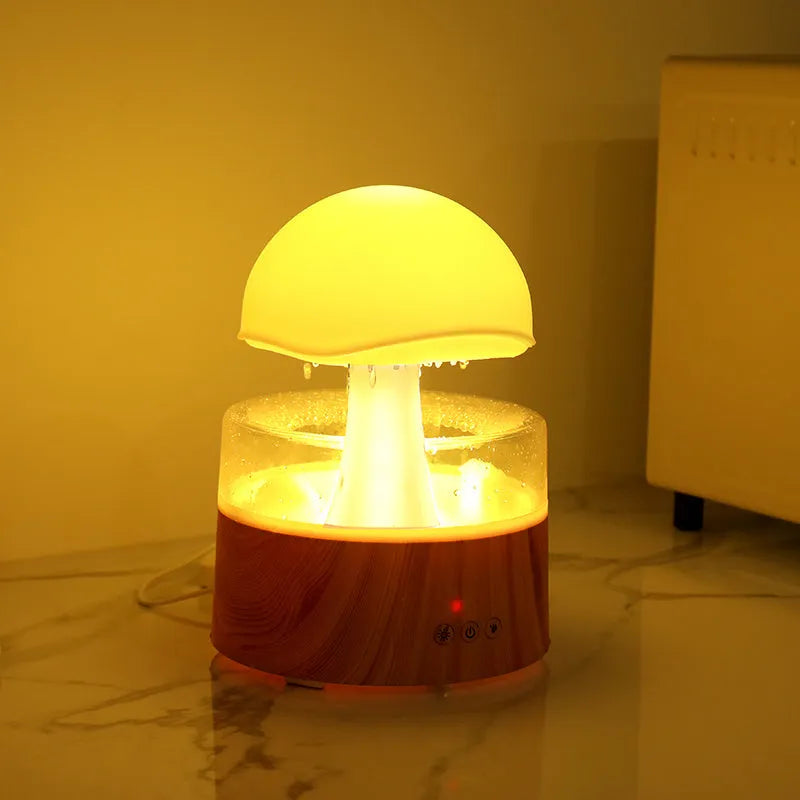 White cloud-shaped humidifier diffuser with LED rain effect and remote control on a wooden table.