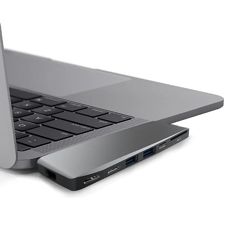 Silver USB-C multi-port hub for MacBook Pro with eight interface ports including USB, card slots, and display output
