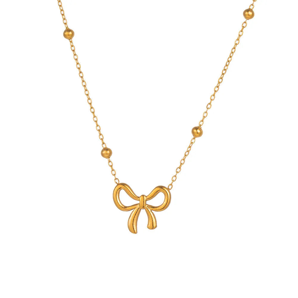 Gold electroplated bow necklace with adjustable chain on dark background