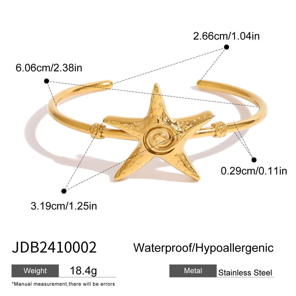 Stainless steel open-ended bracelet with starfish charm on a flat surface