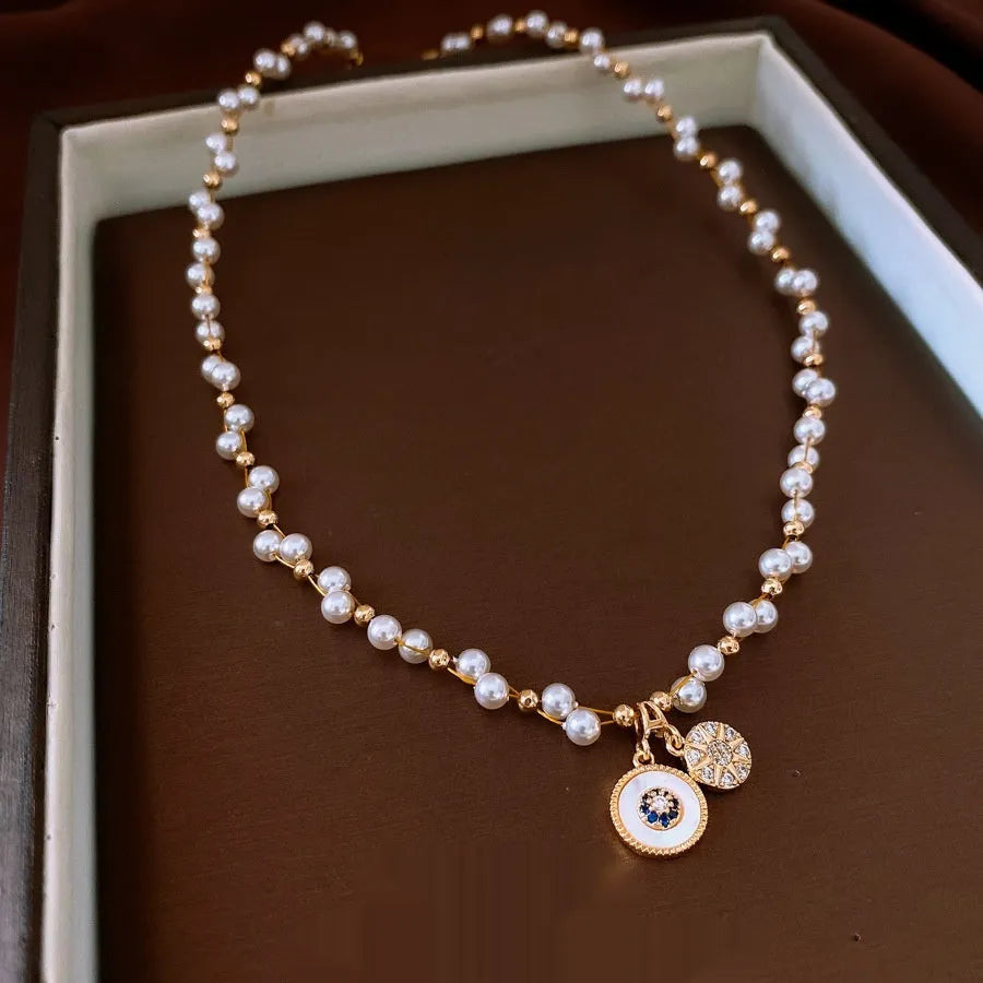 Gold electroplated clavicle necklace with round geometric pendant containing zircon inlay and imitation pearl centrepiece