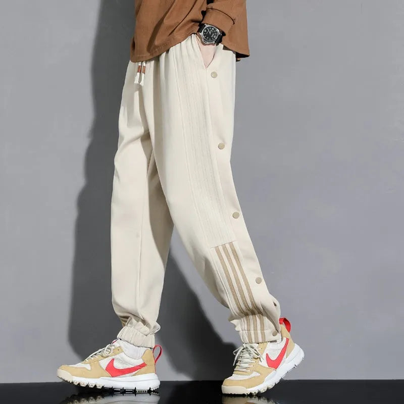 Man wearing loose grey cotton blend sweatpants with ankle ties and a drawstring waist.
